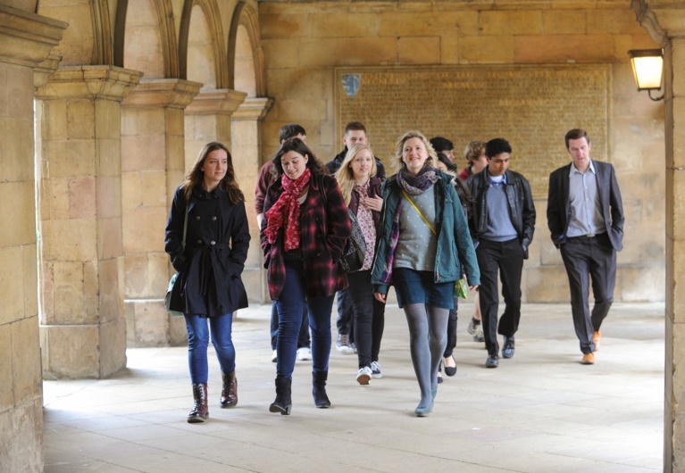 Access Officer & students walking through Chapel Cloisters, with war memorial in the background