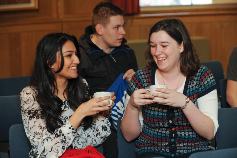 Three students enjoying coffee in a seminar room