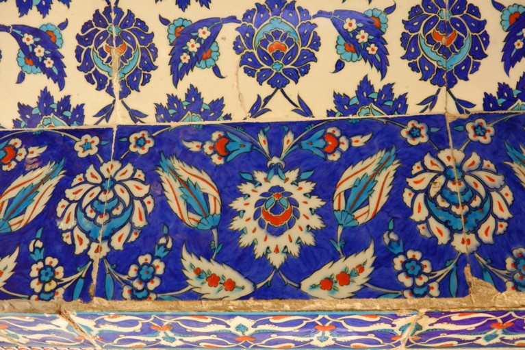 Three rows of red, white and blue tiles, painted with leaves and flowers in a patterned and geometric formation