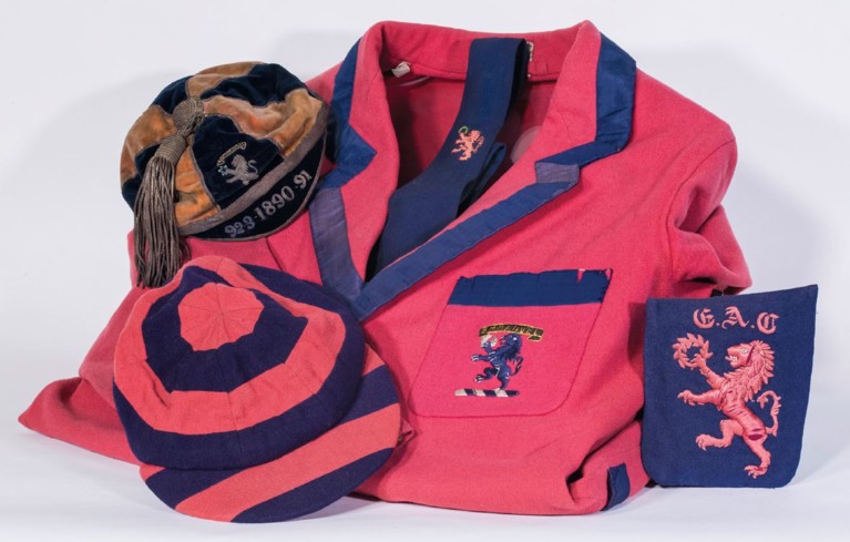 A tableau of pink and blue clothes: two caps, a tie, a jacket and a patch
