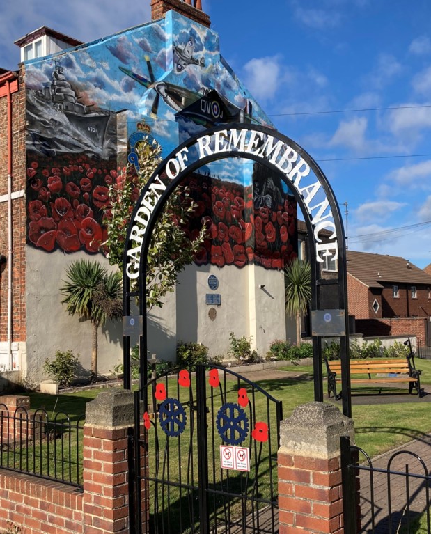 An image of a garden of remembrance with an iron gate reading this