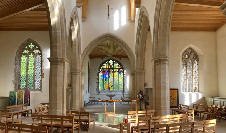 The inside of a stone church with white walls, stone columns and pointed arch windows