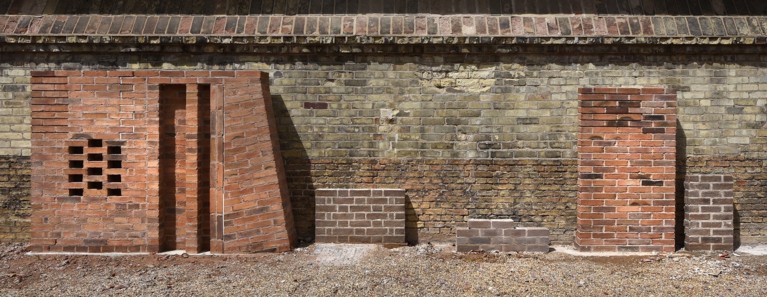 Two brick samples standing against a brick wall