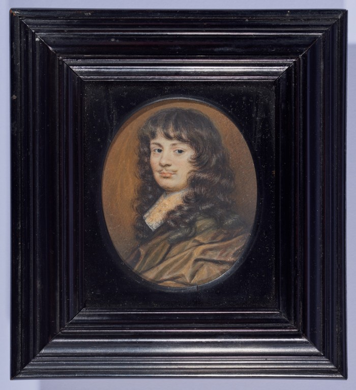 A circular painted minature of a young man with a small moustache, long curled brown hair, a white cravat and a brown silk robe