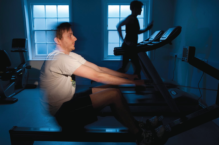 Student on rowing machine, and another behind on a treadmill